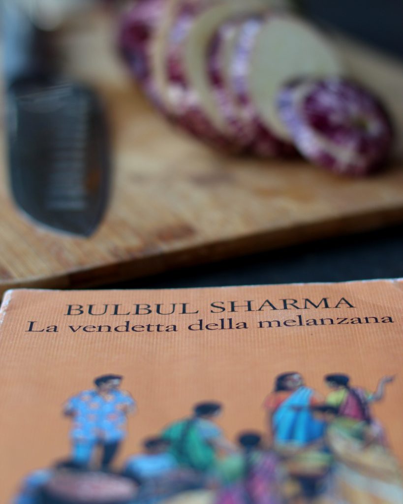 Copertina dell'articolo dedicato alla revisione dei testi. In primo piano il libro: La vendetta della melanzana di Bulbul Sharma. Sullo sfondo c'è un tagliere con un coltello e una melanzana affettata.
